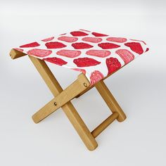 a small wooden stool with a red and white patterned seat cover on it's legs