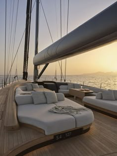 the sun is setting over the deck of a boat with white couches on it