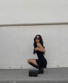 a woman kneeling on the ground with her legs crossed, wearing black boots and sunglasses