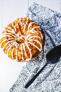 a cake with icing sitting on top of a table next to a fork and spoon