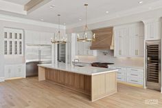 a large kitchen with white cabinets and wood floors, along with an island in the middle