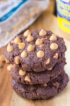 three chocolate cookies with peanut butter on top are stacked next to a jar of peanut butter