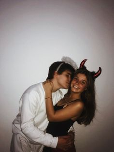 a man and woman dressed up in devil horns hugging each other while posing for the camera