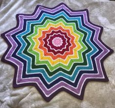 a multicolored crocheted blanket is laying on the ground