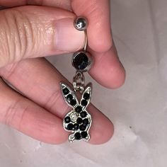 a person is holding a black and white bunny earring