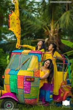 two women sitting on top of a colorful car