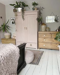 a bedroom with pink furniture and plants on top of the dresser in front of it