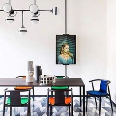 a dining room table with chairs and a painting hanging on the wall behind it,