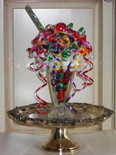 a glass vase filled with candy and streamers on top of a metal tray in front of a door