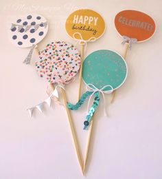 three birthday cake toppers on sticks with confetti