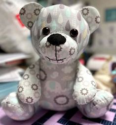 a teddy bear sitting on top of a purple and white checkered tablecloth covered floor