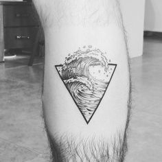 a black and white photo of a man's leg with a wave tattoo on it