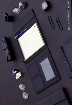 an assortment of office supplies laid out on top of a black surface with writing utensils