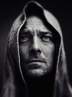 a man wearing a hoodie looking at the camera with an intense look on his face