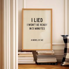 a pile of books sitting on top of a wooden floor next to a framed poster