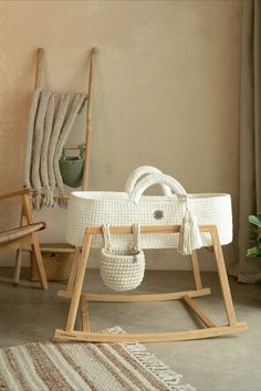 a white wicker baby's cradle next to a rocking chair and potted plant