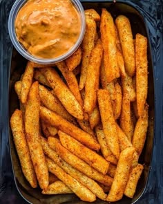 french fries in a pan with dipping sauce on the side, ready to be eaten