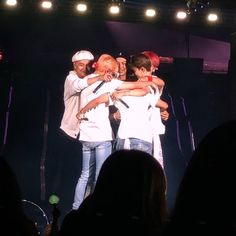 group of people hugging each other on stage with lights in the background