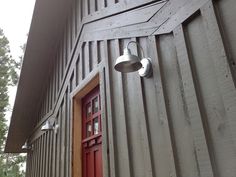 the side of a building with a red door and light fixture hanging from it's side