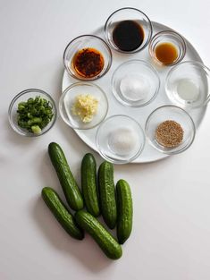 a plate with cucumbers, spices and seasonings on it next to other ingredients