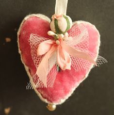 a heart shaped ornament with a pink bow hanging from it's side