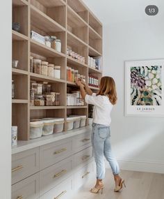 a woman standing in front of a large wooden shelf filled with lots of food items