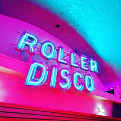 a neon sign that reads roller disco on the side of a building with blue and pink lights