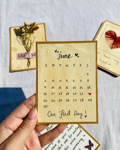 someone is holding up a calendar card with flowers on it, and two other cards