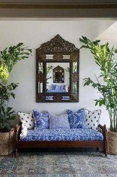 a living room with couches, mirrors and potted plants