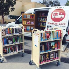 two bookshelves with wheels are parked in front of a book truck