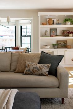 a living room filled with furniture next to a window covered in bookshelves and windows