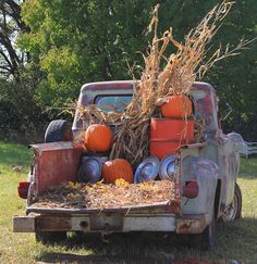 an old pick up truck with pumpkins in the bed and hay on the back