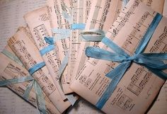 five old sheet music sheets with blue ribbons tied around them on top of an open book