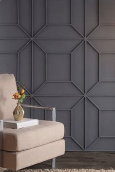 a chair with a vase on top of it in front of a wall that has geometric panels