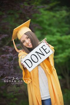 a young woman wearing a graduation gown and holding a sign that says donee in front of her