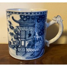 a blue and white coffee mug sitting on top of a wooden table next to a wall