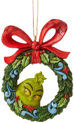 a christmas ornament hanging from a red ribbon on a white background with a green wreath