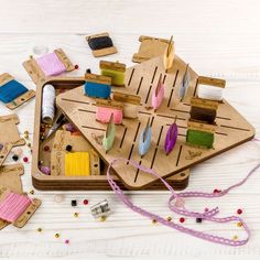 an assortment of crafting supplies laid out on a wooden tray with string and beads