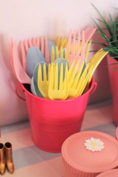 colorful plastic utensils in pink pails with flowers on the rims and gold forks