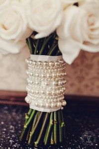 a bouquet of white roses and pearls in a vase