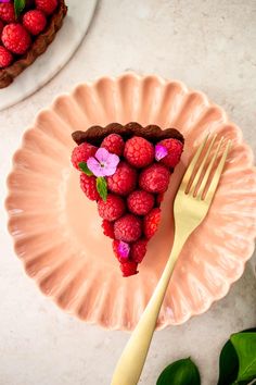 a heart shaped piece of chocolate cake with raspberries on it and a fork