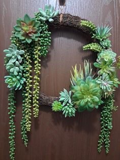 a wreath with succulents hanging on a wooden wall next to a bird