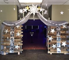 an entrance to a party decorated with wooden pallets and white stars hanging from the ceiling