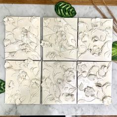 four white tiles with green leaves on the top and one is made out of marble