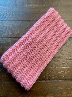 a pink crocheted headband sitting on top of a wooden floor