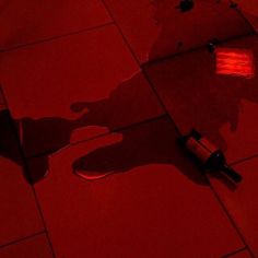 a red light shines on the floor next to a toothbrush and razor blade