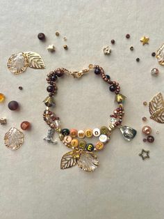 an assortment of beads and charms on a white surface, including a bracelet with leaves