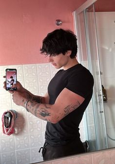 a man taking a selfie in front of a bathroom mirror with his cell phone