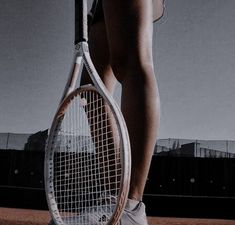 a woman holding a tennis racquet on top of a tennis court with buildings in the background