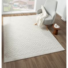 a living room area with a chair and rug on the hardwood floor next to a window